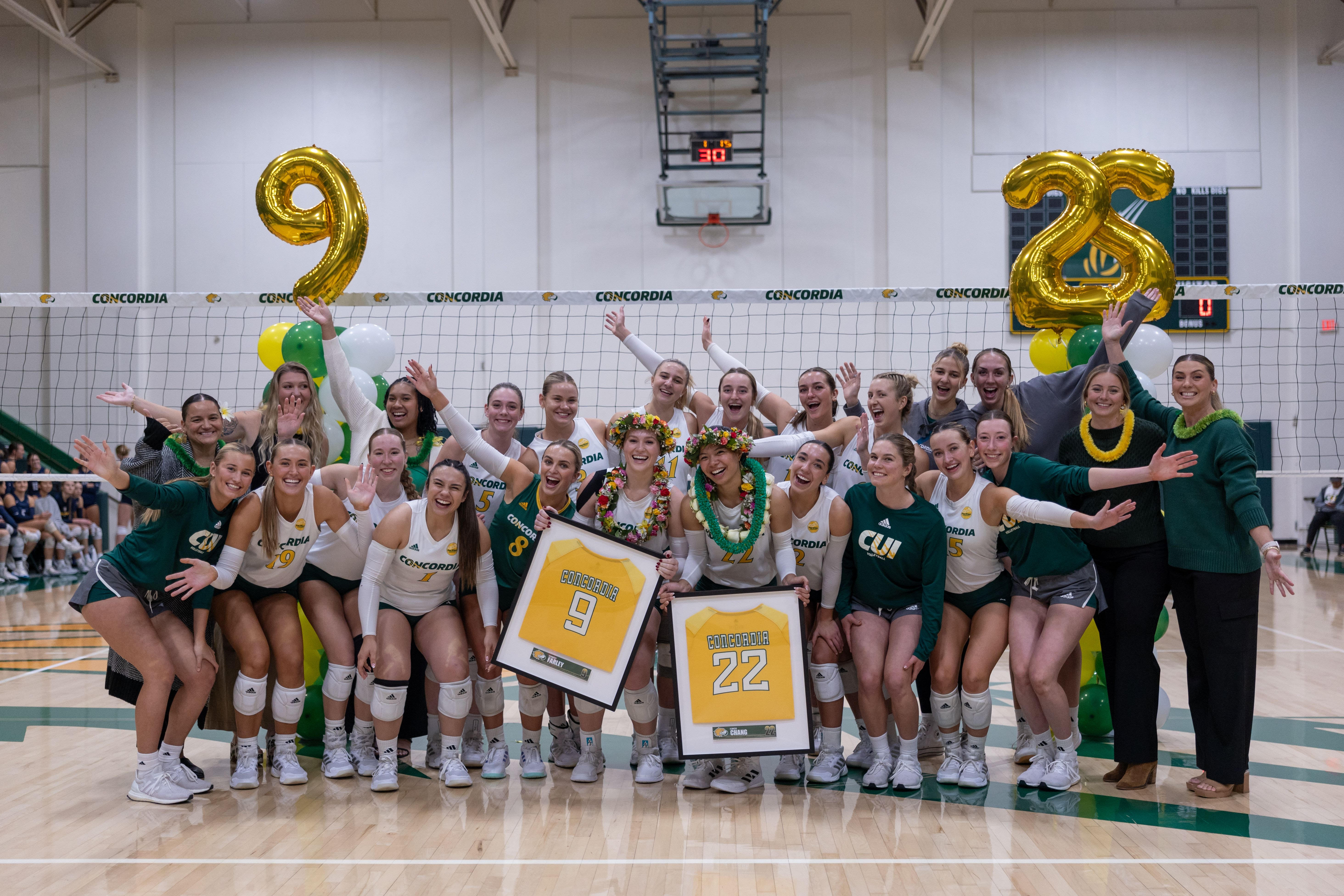 Concordia women’s volleyball team with seniors, Kennedy Farley and Kawhi Chang with holding framed jerseys